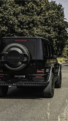 a black jeep is parked in front of some trees