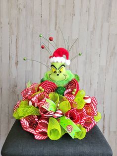 a green stuffed animal sitting on top of a pile of red and green candy canes