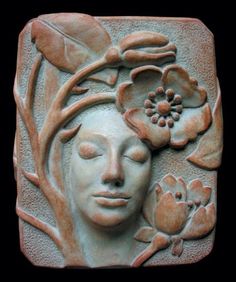 a ceramic face with flowers and leaves on it's head, in the shape of a woman's head