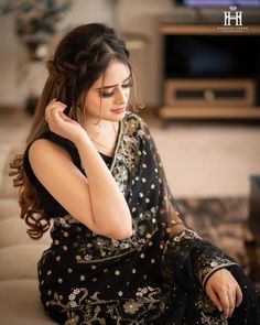 a woman sitting on top of a couch wearing a black dress