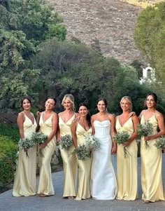 a group of women standing next to each other in front of some trees and bushes