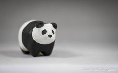 a small black and white panda bear figurine on a gray background with space for text