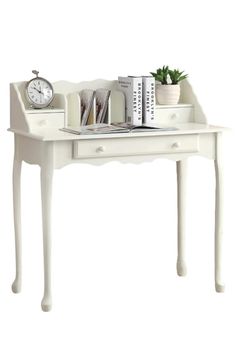 a white desk with books and a clock on it's side table next to a potted plant