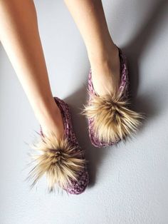 a woman's feet wearing slippers with furry pom - poms