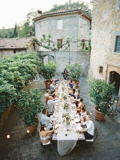 a group of people sitting at a long table in the middle of an alleyway