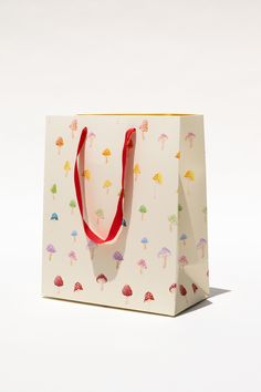 a white shopping bag with colorful umbrellas printed on the front and sides, sitting against a white background