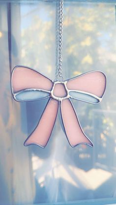 a pink and white bow hanging from a window