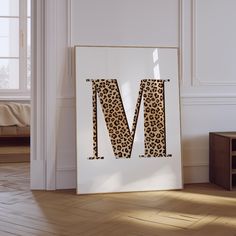 the letter m is made out of leopard print paper and sits in front of a white wall