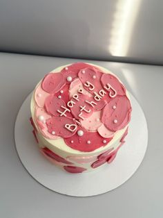 a birthday cake with pink frosting and hearts on the top is sitting on a white plate