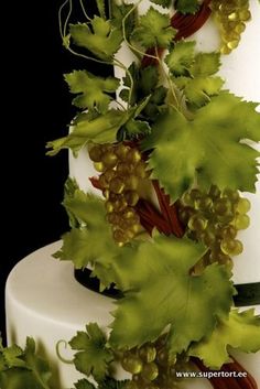 a wedding cake decorated with green leaves and grapes