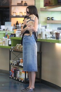 a woman standing in front of a counter holding a dog