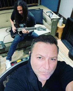 two men are playing guitars in a living room