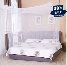 a bed with a mosquito net over it and pillows on the bottom, in front of a window