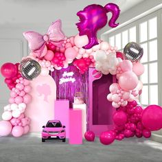 a car is parked in front of a pink and purple balloon arch with lots of balloons