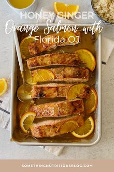 honey ginger orange salmon with florida oj in a baking dish next to lemons and rice