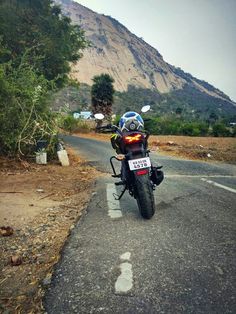 the motorcycle is parked on the side of the road in front of a large mountain