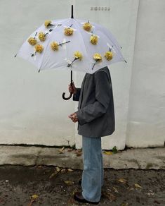 a man standing under an umbrella with flowers on it and holding an umbrella in his hand