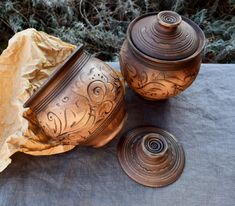 two brown vases sitting next to each other on top of a cloth covered table