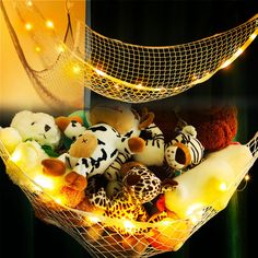 a basket filled with lots of stuffed animals sitting on top of a bed covered in lights