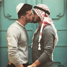 two men standing next to each other and kissing