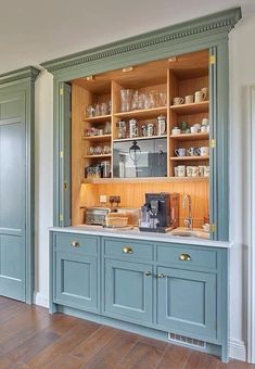 a kitchen with blue cabinets and wooden floors in the center is filled with glassware