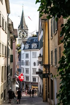 people walking down an alley way with buildings and a clock tower in the background