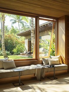 a living room filled with lots of windows and furniture next to a lush green yard