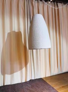 a lamp that is on top of a wooden floor next to a curtained wall