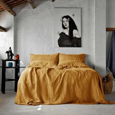 a bed in a room with a painting on the wall above it and an orange bedspread