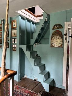 a room with stairs and pictures on the wall next to a clock hanging on the wall