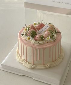 a white cake with pink icing and strawberries on top