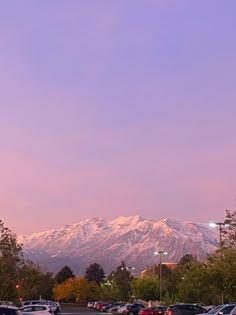 cars are parked in a parking lot with mountains in the background at sunset or dawn