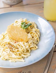 a plate of pasta with parmesan cheese and herbs on it next to a glass of orange juice