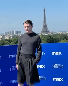 a man standing in front of the eiffel tower with his hands in his pockets