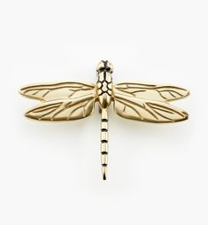 a gold dragonfly brooch sitting on top of a white surface