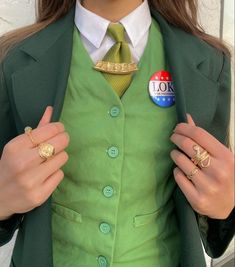 a woman in a green suit and tie holding two rings