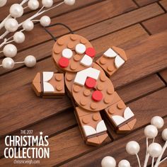 a gingerbread man made out of legos on a wooden table with white and red decorations