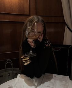 a woman sitting at a table with a glass of wine