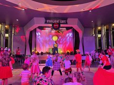 children are dancing in front of a stage with an image of a man on it