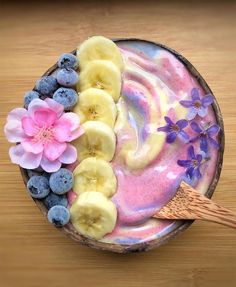 a bowl filled with yogurt, bananas and blueberries on top of a wooden table