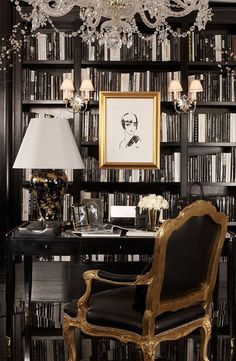 a chair in front of a bookcase with chandelier hanging from the ceiling