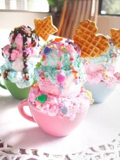 three cups filled with ice cream and sprinkles on top of a table