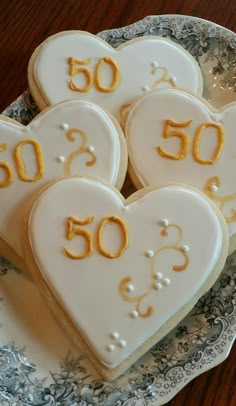 three heart shaped cookies with the number 50 on them are sitting on a blue and white plate