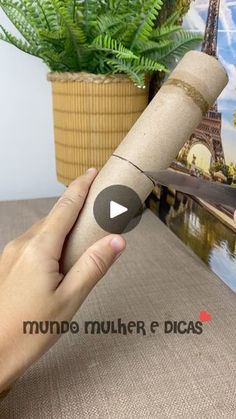 a hand holding a rolled up piece of paper with the eiffel tower in the background