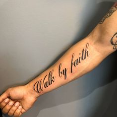 a person with a tattoo on their arm that says walk by faith