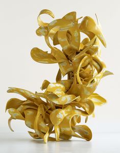 an abstract sculpture made out of yellow and white paper with flowers on it's sides