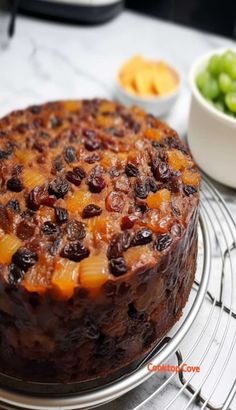 a pineapple upside down cake with raisins and grapes on the side sitting on a cooling rack