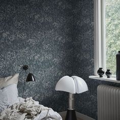 a bedroom with blue wallpaper and a white lamp next to the radiator