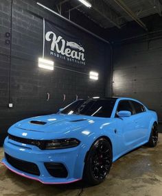 a blue dodge charger is parked in a garage with the kleain logo on it