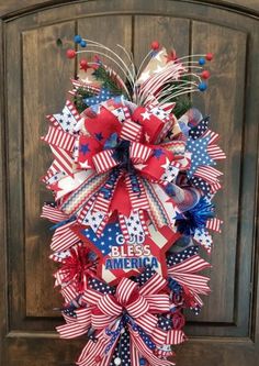 a patriotic wreath with red, white and blue bows on it is hanging from the front door